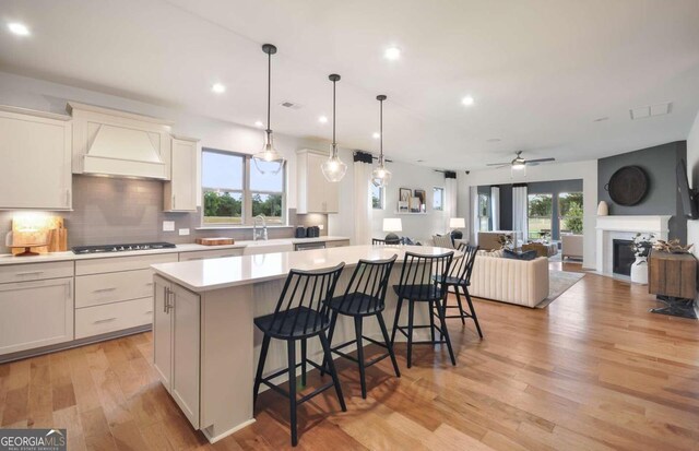 kitchen featuring custom exhaust hood, a breakfast bar area, black gas cooktop, and a center island