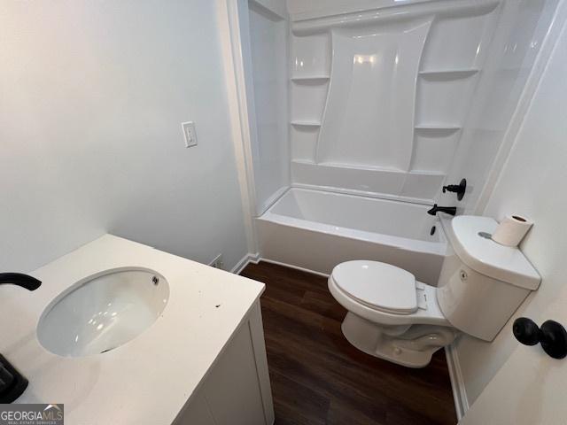 full bathroom with hardwood / wood-style floors, vanity, shower / bathtub combination, and toilet