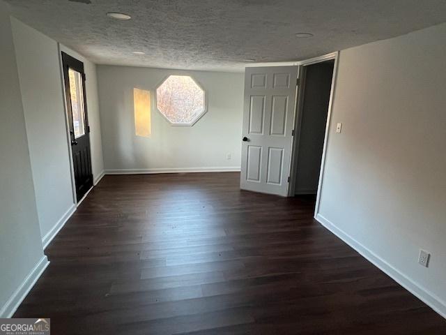 empty room featuring a textured ceiling and dark wood-type flooring