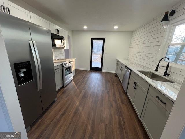 kitchen featuring white cabinetry, sink, dark wood-type flooring, stainless steel appliances, and decorative backsplash