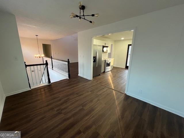 spare room with a notable chandelier and dark hardwood / wood-style flooring