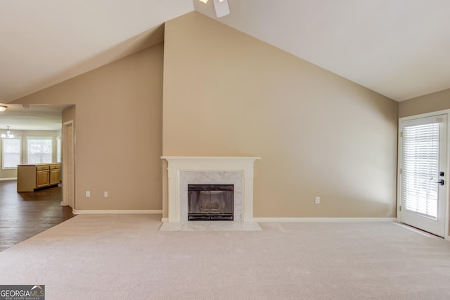 unfurnished living room featuring a premium fireplace, vaulted ceiling, and carpet flooring