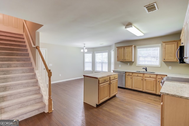 kitchen with sink, hardwood / wood-style flooring, hanging light fixtures, light brown cabinetry, and stainless steel dishwasher