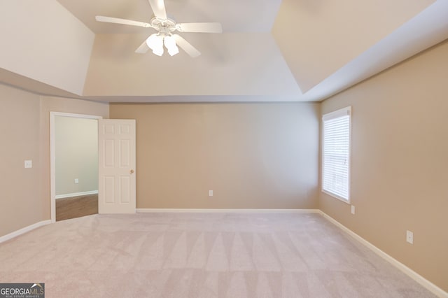 carpeted empty room featuring a raised ceiling and ceiling fan