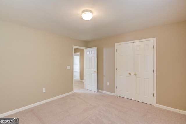 unfurnished bedroom with light carpet and a closet