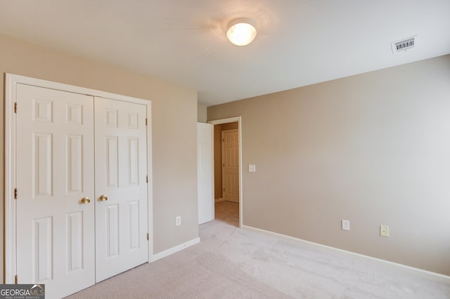 unfurnished bedroom with light colored carpet and a closet