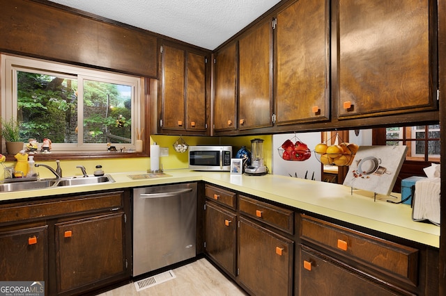 kitchen featuring stainless steel appliances, dark brown cabinets, sink, and a textured ceiling