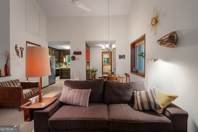 living room featuring ceiling fan with notable chandelier, light colored carpet, and high vaulted ceiling