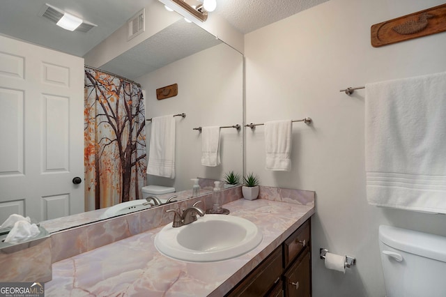 bathroom featuring vanity, a textured ceiling, and toilet