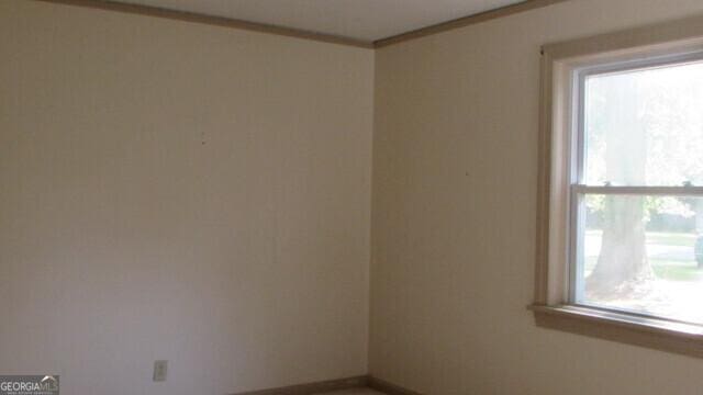 empty room with ornamental molding and a healthy amount of sunlight