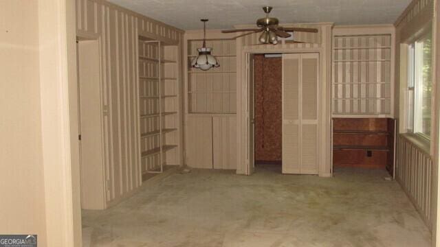 interior space with ornamental molding, light carpet, and ceiling fan