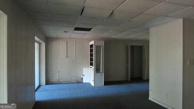 unfurnished room with dark colored carpet and a paneled ceiling