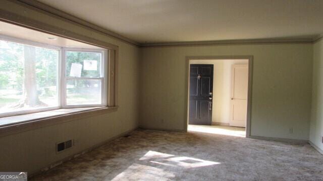 unfurnished room featuring ornamental molding and light colored carpet