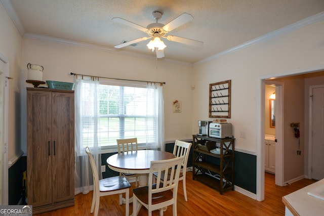 dining area with crown molding, baseboards, a ceiling fan, and light wood-style floors