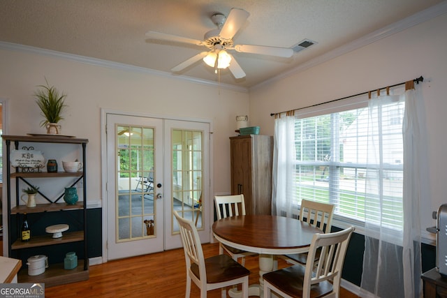 dining area featuring light wood-style floors, ceiling fan, ornamental molding, visible vents, and french doors