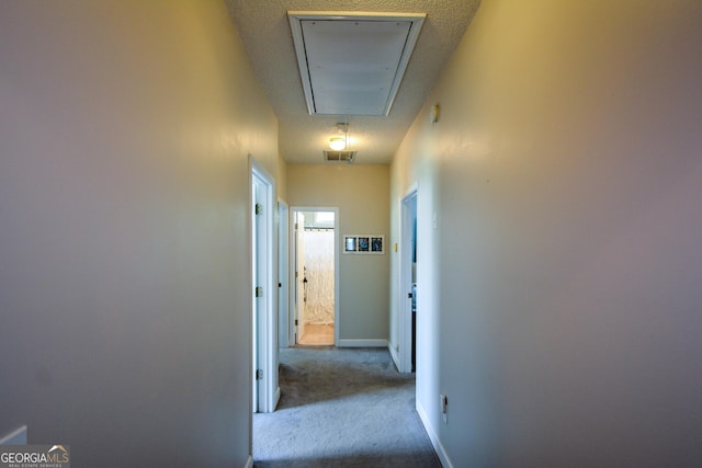 corridor with visible vents, baseboards, attic access, and carpet floors