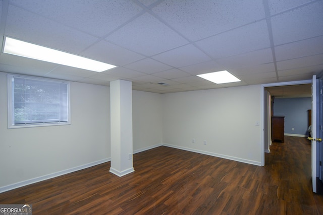 finished basement with dark wood-style floors, baseboards, and a drop ceiling