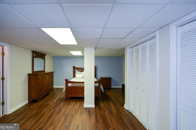 bedroom with a paneled ceiling, wood finished floors, and baseboards