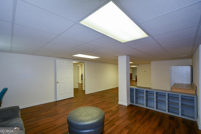 finished below grade area featuring a paneled ceiling, baseboards, and wood finished floors