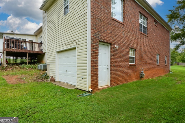 view of side of home with a yard, an attached garage, central AC unit, and brick siding