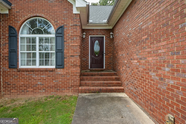 entrance to property with brick siding and a shingled roof