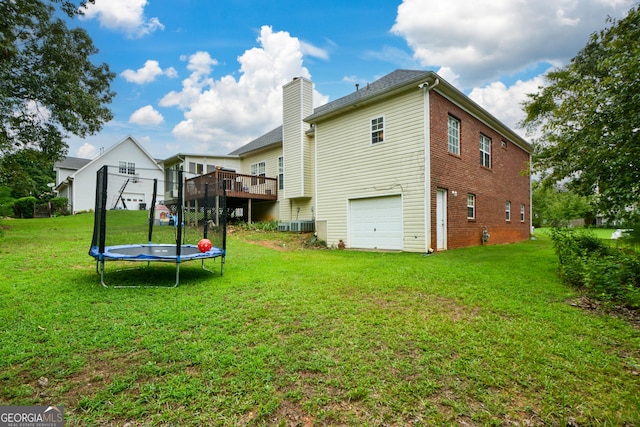 back of property featuring a yard, an attached garage, a trampoline, and a chimney