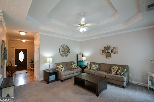 carpeted living room with a tray ceiling, crown molding, a ceiling fan, and visible vents