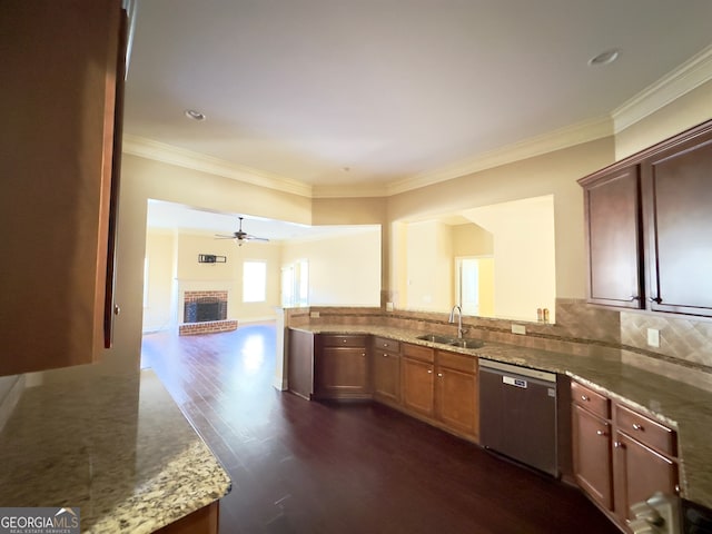 kitchen featuring a brick fireplace, crown molding, dark wood-type flooring, sink, and stainless steel dishwasher