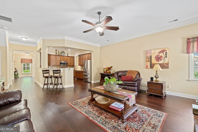 living room with dark wood-type flooring, crown molding, a wealth of natural light, and ceiling fan