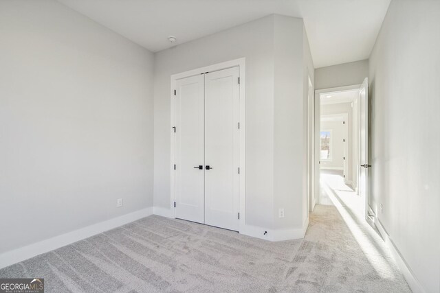 unfurnished bedroom featuring a closet and light colored carpet