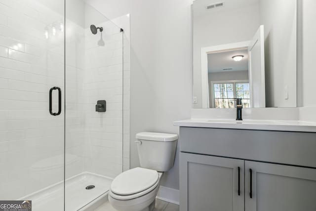 bathroom with vanity, toilet, and a shower with door