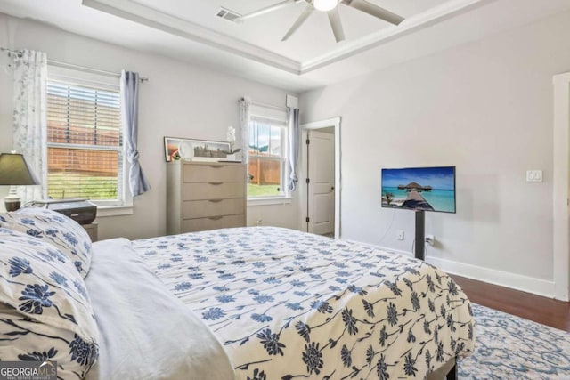 bedroom featuring ceiling fan, dark wood-type flooring, and a tray ceiling