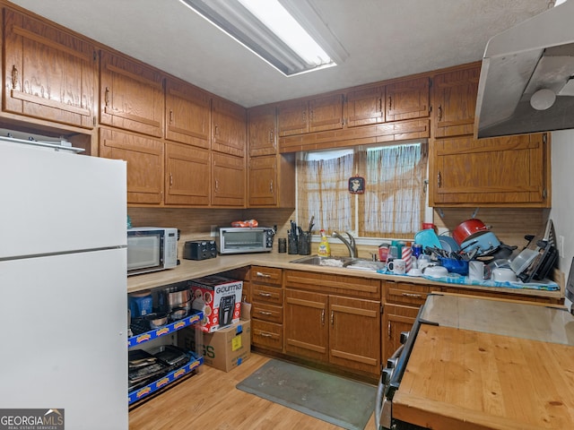 kitchen with sink, white appliances, light hardwood / wood-style flooring, and exhaust hood