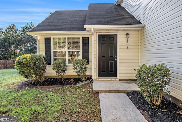 view of exterior entry featuring a lawn