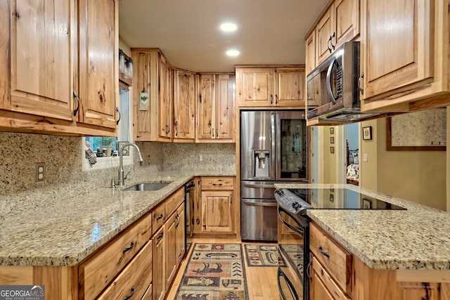 kitchen featuring backsplash, light stone countertops, light wood-type flooring, and stainless steel appliances