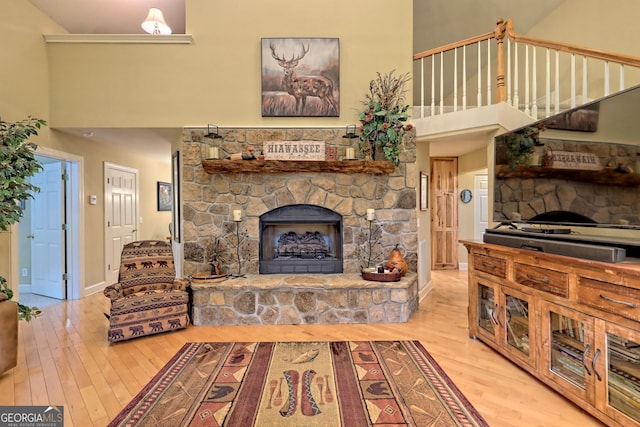 living room with a fireplace, light hardwood / wood-style flooring, and a high ceiling