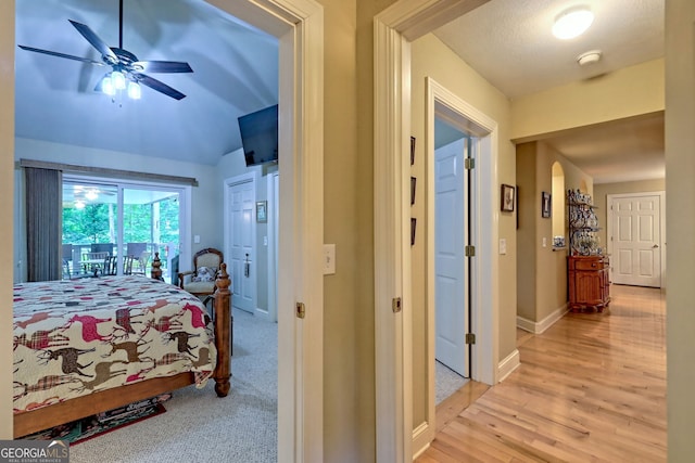 bedroom with access to exterior, light colored carpet, vaulted ceiling, and ceiling fan