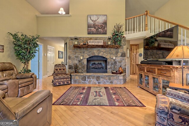 living room featuring high vaulted ceiling, a fireplace, and light hardwood / wood-style flooring