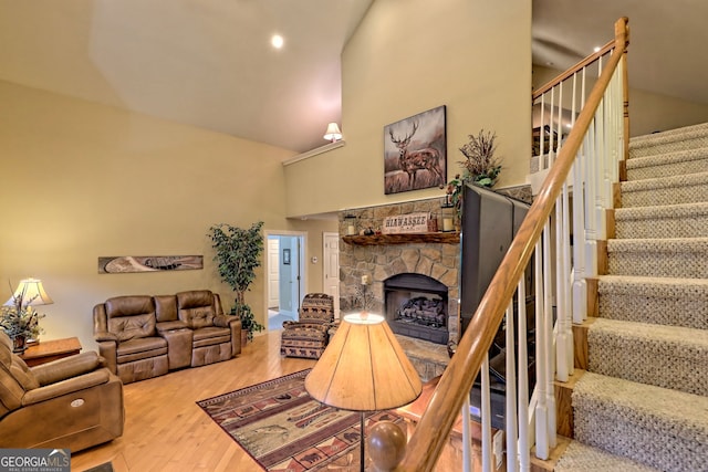 living room with high vaulted ceiling, a fireplace, and hardwood / wood-style floors