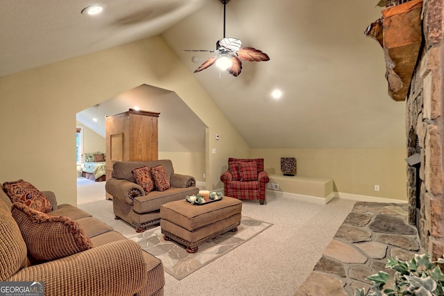 living room featuring a stone fireplace, lofted ceiling, light carpet, and ceiling fan