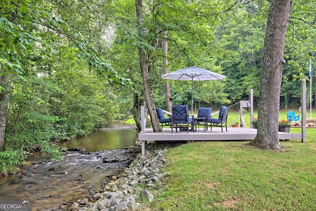 dock area featuring a deck with water view and a lawn