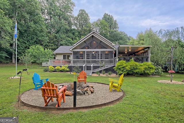 view of playground featuring a sunroom, a deck, a yard, and an outdoor fire pit