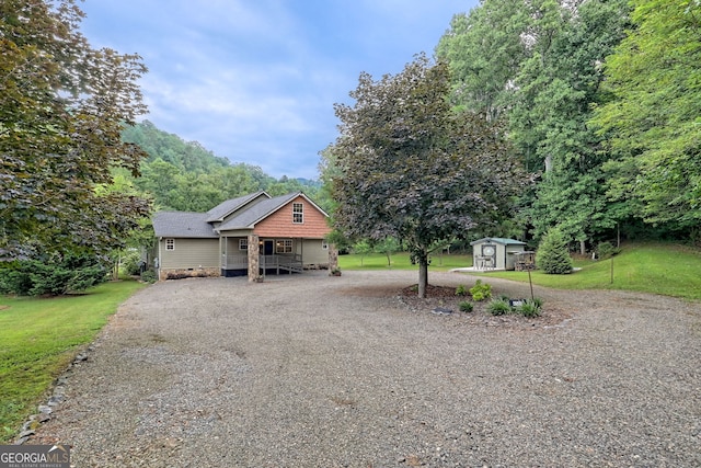 view of front of house with a storage unit and a front lawn