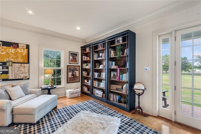 living area featuring wood-type flooring, a wealth of natural light, and crown molding