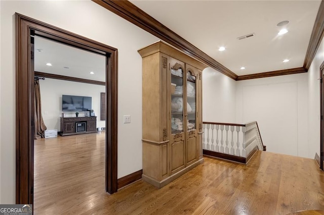 hallway featuring light wood-type flooring and crown molding