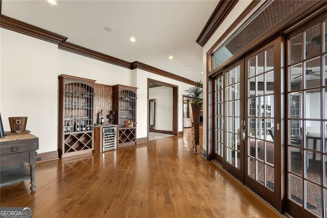 hall featuring wood-type flooring, beverage cooler, ornamental molding, and french doors