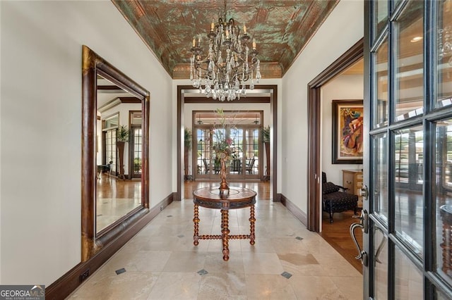 corridor featuring a notable chandelier, crown molding, and french doors