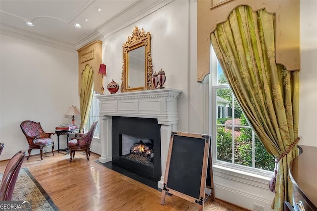 sitting room with ornamental molding and light hardwood / wood-style floors