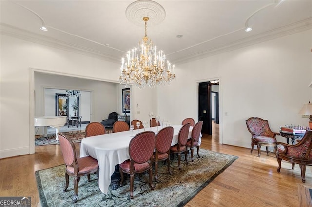 dining area with light wood-type flooring, a chandelier, and crown molding