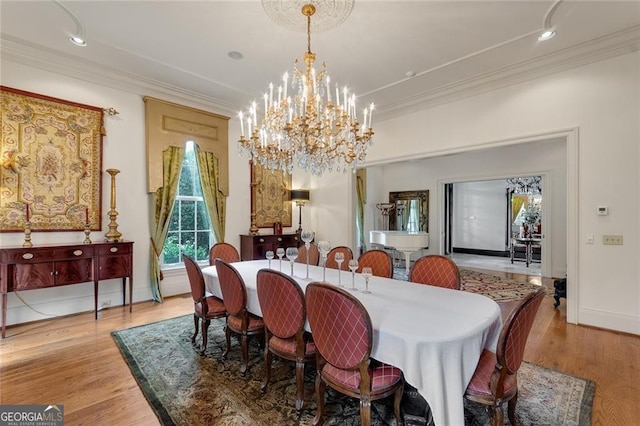 dining space with ornamental molding, a notable chandelier, and light wood-type flooring